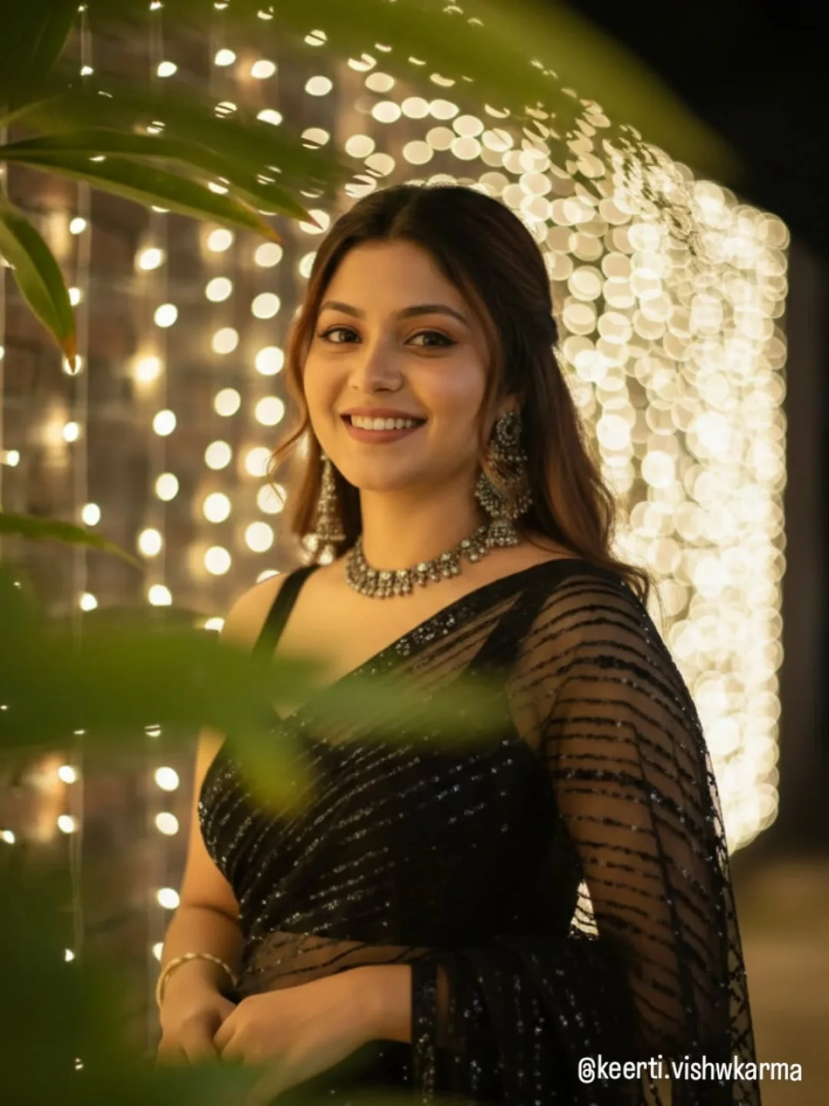 Confident Young Woman in Elegant Black Net Saree Amidst Fairy Lights at Night