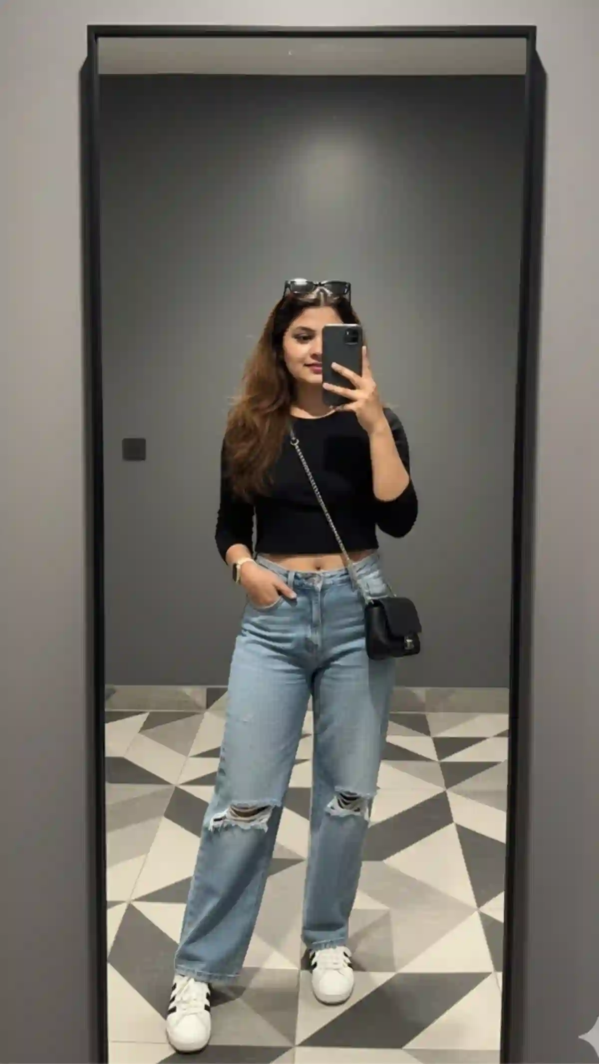 Stylish Full-Body Mirror Selfie of a Young Woman in Black Crop Top and Ripped Wide-Leg Jeans